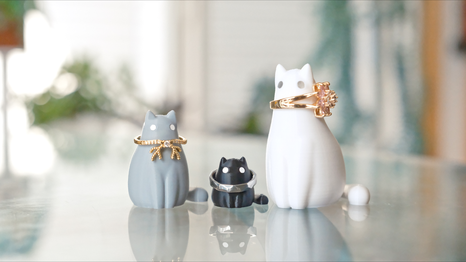 Three mini cat shaped figurines holding rings on their necks