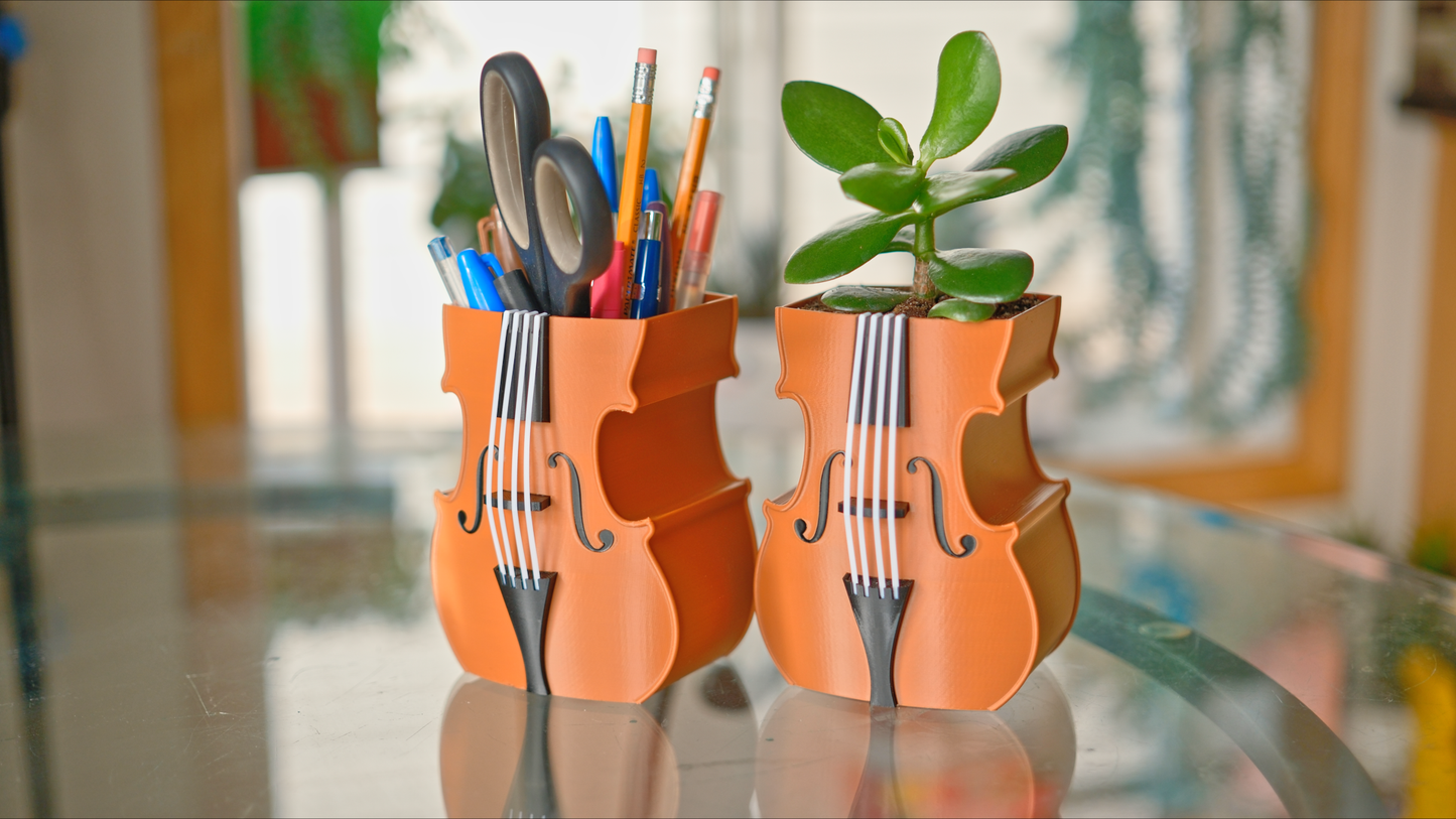 violin shaped plant pots holding stationery pens and pencils and scissors, and a plant